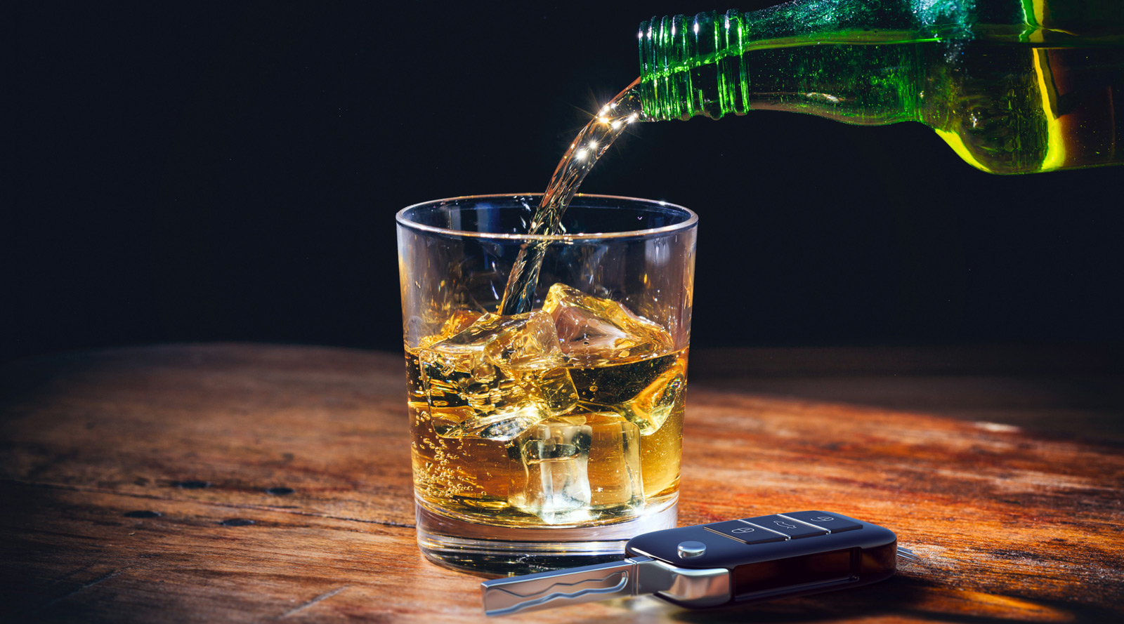 Car key and alcohol glass on wooden background