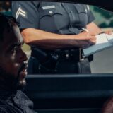 Interior close-up of driver at traffic stop with window down and police officer standing outside driver's window